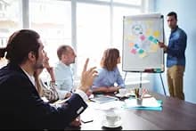Personnes dans une salle regardant un expert avec un tableau et des postits