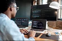 Développeur codant sur un PC devant 3 écrans