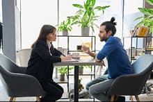 Deux personnes face à face discutant autour d'une table